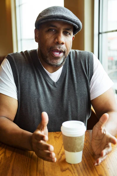 Volwassen Afrikaanse Amerikaanse man zit in een koffieshop. — Stockfoto