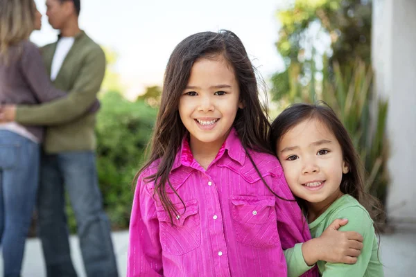 Gelukkig weinig meisjes met hun ouders op de achtergrond. — Stockfoto