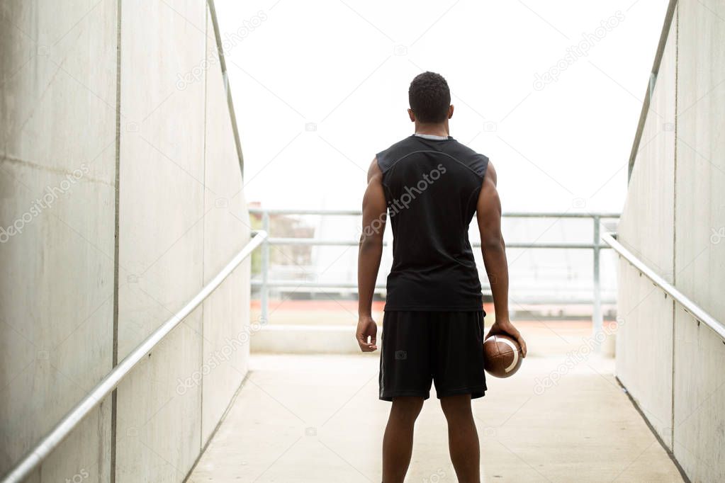 Rear view of a football player holding a fooball.