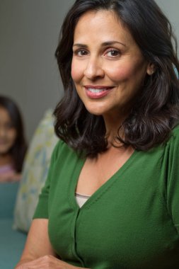 Güzel kendine güvenen İspanyol gülümseyen kadın arka planda bir çocukla.