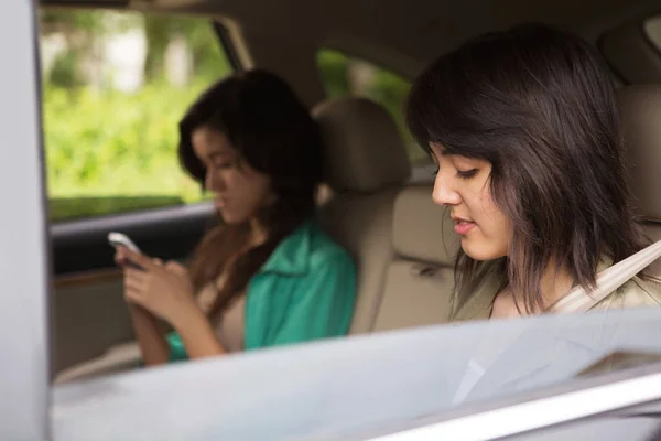 Adolescente niñas mensajes de texto en el asiento trasero . —  Fotos de Stock