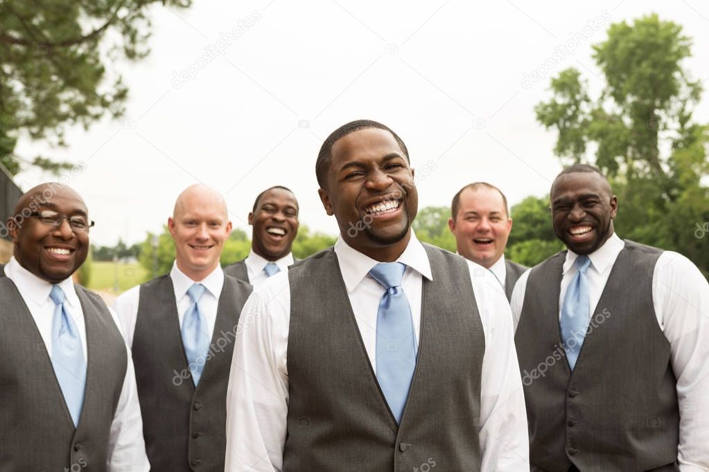 Groom and groomsmen smiling at a wedding.