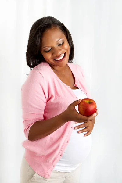 Bir elma ile sağlıklı Afro-Amerikan hamile kadın. — Stok fotoğraf