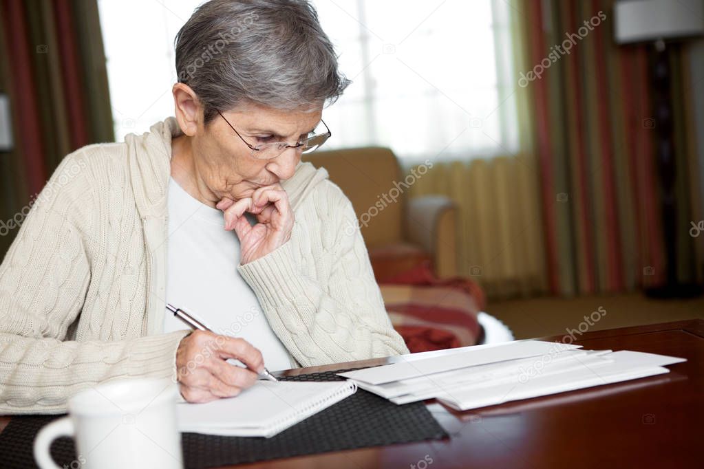 Mature elderly woman paying the bills.