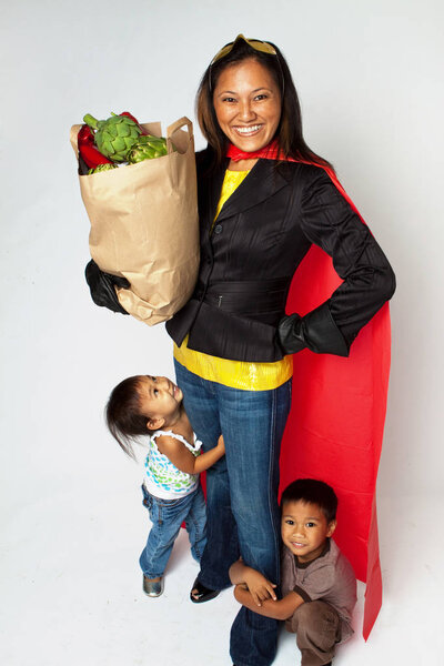 Мама-супергерой со своими детьми, держащими в руках булочки
.