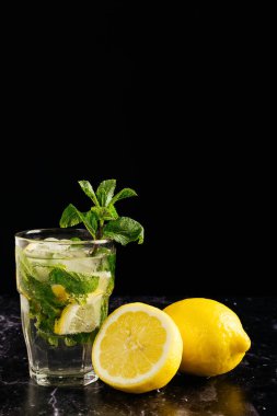 Bir bardak mojito, bir tutam nane ve koyu arkaplanda limon ile süslenmiş. yatay resmi kapat