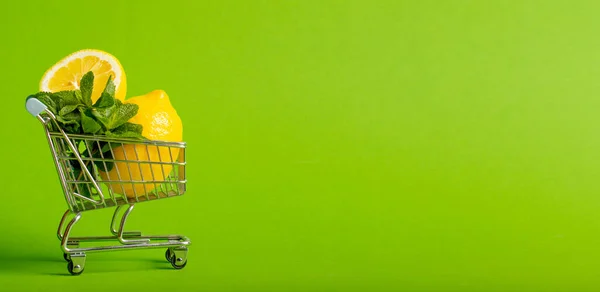 Citroner och mynta i en liten leksaksvagn på en grön bakgrund. Nätbutikers leveranskoncept. du kan använda den som banner med din text — Stockfoto