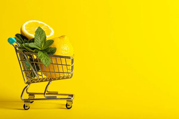 Citroner och mynta i en liten leksak vagn på en banan gul bakgrund. Nätbutikers leveranskoncept. horisontell vy — Stockfoto