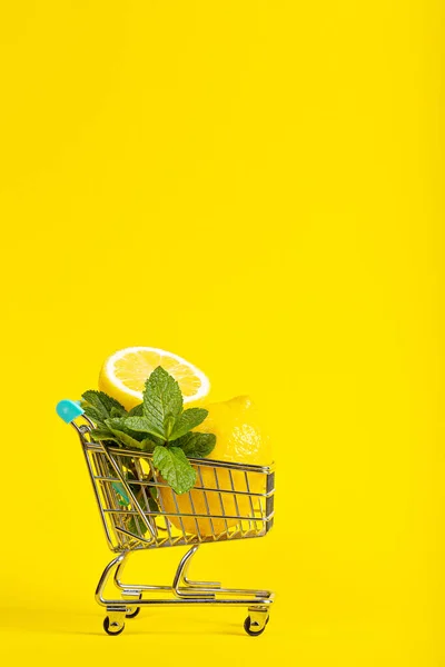 Citroner och mynta i en liten leksak vagn på en banan gul bakgrund. Leveranskoncept online — Stockfoto