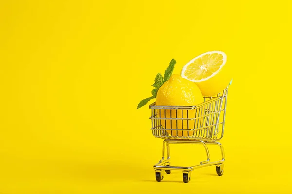 Citroner och mynta i en liten leksak vagn på en banan gul bakgrund. Nätbutikers leveranskoncept. horisontell vy — Stockfoto