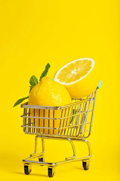 Citroner och mynta i en liten leksak vagn på en banan gul bakgrund. Leveranskoncept online — Stockfoto