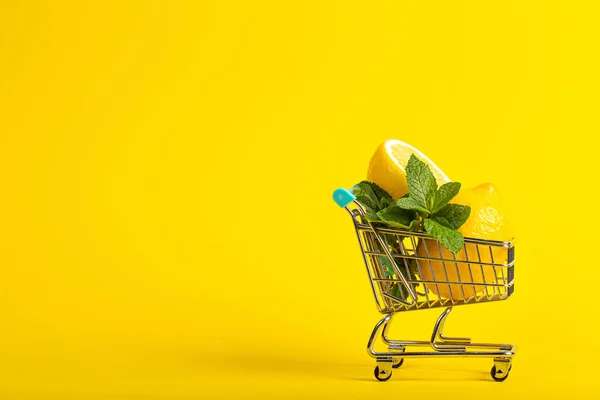 Limões e hortelã em um carrinho de brinquedo pequeno em um fundo amarelo de banana. conceito de entrega loja online. vista horizontal — Fotografia de Stock