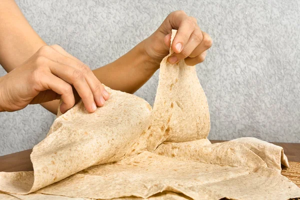 hands tear off a piece of pita bread, closeup