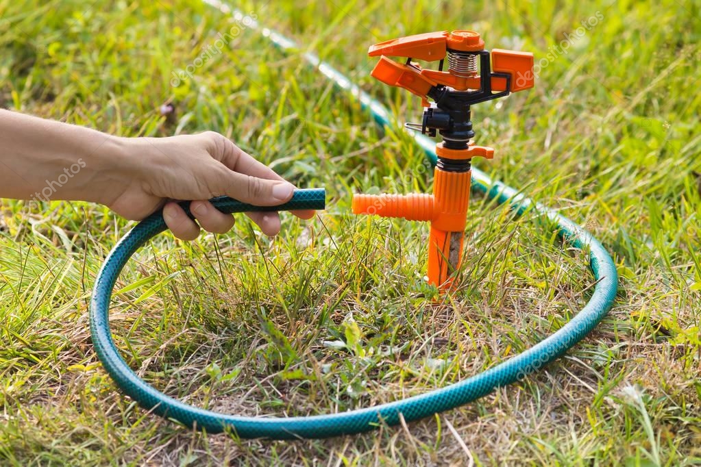 Hand of gardener installing sprinkler for irrigation of lawn — Stock