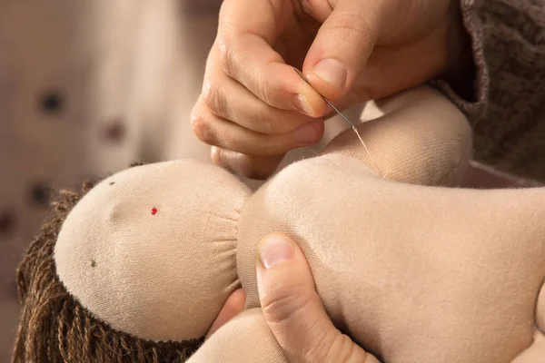 hands sewing a Waldorf doll