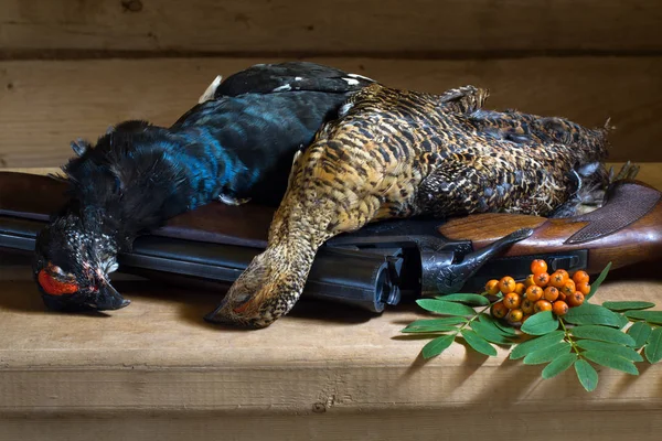 Two downed grouses and Rowan berries lie on a wooden table on to — Stock Image Two downed grouses and Rowan berries lie on a wooden table on to Stock Photo
