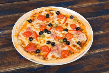 Domates soslu taze pizza, siyah zeytin, mozzarella peyniri, ahşap masada jambon.