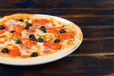 Domates soslu taze pizza, siyah zeytin, mozzarella peyniri, ahşap masada jambon.