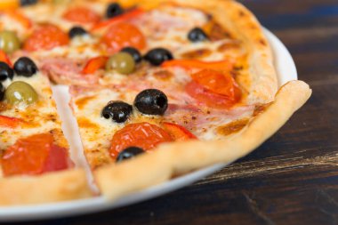 Domates soslu taze pizza, siyah zeytin, mozzarella peyniri, ahşap masada jambon.