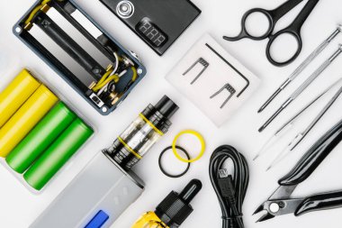 Beyaz arka planda modern buharlaşma cihazının bakımı ve montajı için araç gereç kiti. sökülmüş tüp mod, piller, buhar cihazı, uygun şişe, usb kablosu, cımbız, makas, makas...
