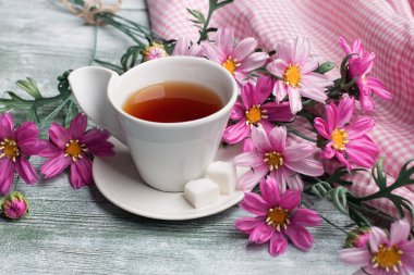 Yapay kozmos bipinnatus yeşil ahşap masa üzerinde çay kapağı ile