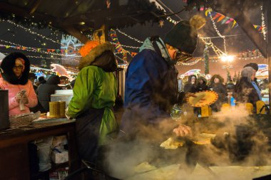 MOSCOW, RUSSIA - 5 HAZİRAN 2017: Moskova 'daki Kızıl Meydan' da Noel pazarında insanlar, Noel pazarında Atlıkarınca sallanıyor. St. Arka planda Basil Katedrali (kar fırtınası).