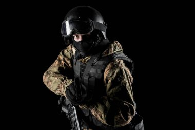 Bir asker saldırı tüfeği tutuyor. Üniforma Rusya Federasyonu 'nun FSB özel hizmetlerine uyuyor. Stüdyoda çekilmiş. Siyah arkaplanda kırpma yolu ile izole edildi