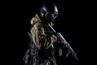 Bir asker saldırı tüfeği tutuyor. Üniforma Rusya Federasyonu 'nun FSB özel hizmetlerine uyuyor. Stüdyoda çekilmiş. Siyah arkaplanda kırpma yolu ile izole edildi