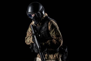 Bir asker saldırı tüfeği tutuyor. Üniforma Rusya Federasyonu 'nun FSB özel hizmetlerine uyuyor. Stüdyoda çekilmiş. Siyah arkaplanda kırpma yolu ile izole edildi