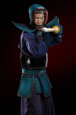 Shinai (bambu kılıcı) ile insan kendo dövüşçüsü portresi. Stüdyoda çekilmiş. Koyu kırmızı arkaplanda kırpma yolu ile izole edilmiş