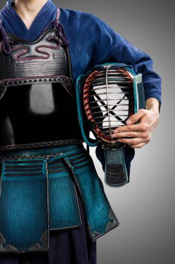 Geleneksel Kendo zırhlı, kasklı bir erkek. Stüdyoda çekilmiş. Gri arkaplanda izole edilmiş 