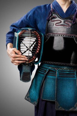 Geleneksel Kendo zırhlı, kasklı bir erkek. Stüdyoda çekilmiş. Gri arkaplanda izole edilmiş 