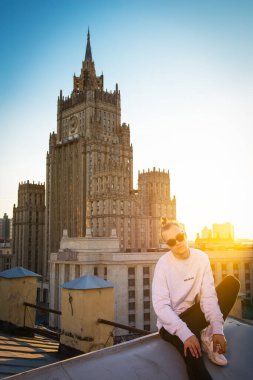 MOSCOW, RUSSIA - 30 Haziran 2016: Yüksek çatılı Dışişleri Bakanlığı binasının arka planında oturan genç ve cesur erkek 