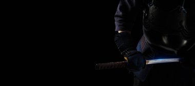 Geleneksel Kendo zırhlı, siyah arka planda samuray kılıcı katanalı bir erkek. (Tanımlanamayan kişi, siyah maske) Stüdyoda vuruldu. Kırpma yolu ile izole edilmiş. Panoramik resim.