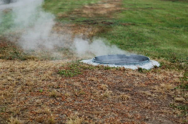 El vapor sale de la alcantarilla — Foto de Stock