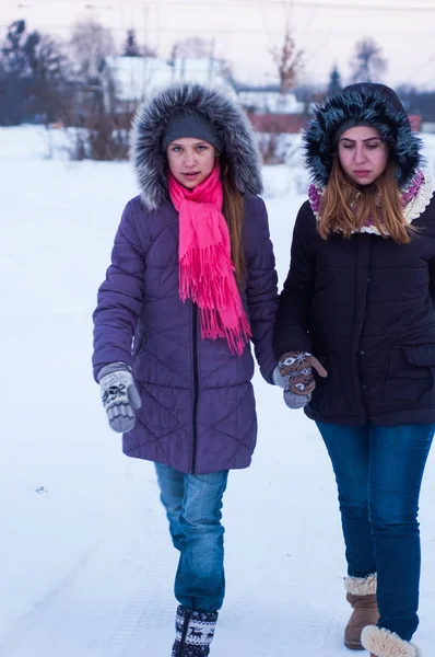 Girls walk in the winter on the street in the snow.