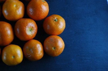 Sert ışık ile karanlık bir arka plan üzerinde soyulmamış mandalina.