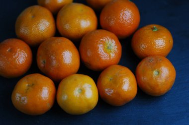 Sert ışık ile karanlık bir arka plan üzerinde soyulmamış mandalina.