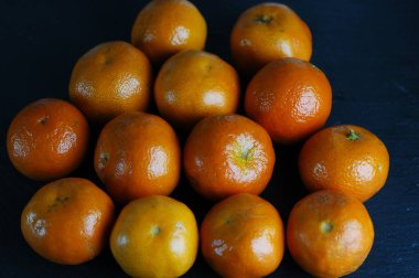 Sert ışık ile karanlık bir arka plan üzerinde soyulmamış mandalina.