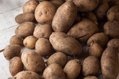 Pis patateslerin rustik bir arka plan üzerine bir sürü.