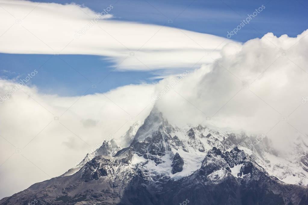 mountains of patagonia in haze at daylight with windy lenticular clouds