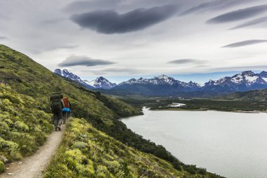 iki adam hiking Patagonya Dağları, torres del paine gri gökyüzü ile