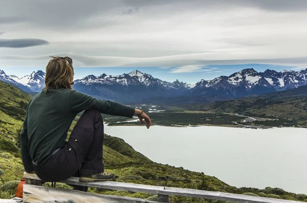 Az ember ül a szürke égbolt Patagonia-tó felett — Stock Fotó