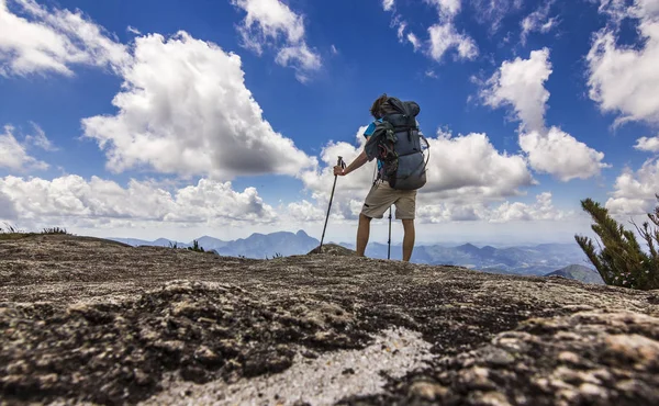 Uomo con zaino in piedi sulla cima della montagna con cielo blu con nuvole — Foto Stock