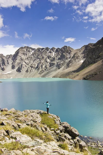 Ragazza in giacca blu in piedi con hands-up sopra il lago blu in montagna — Foto Stock