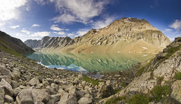 Bellissimo lago di montagna blu con pietre sulla riva e nuvole sul cielo blu — Foto Stock