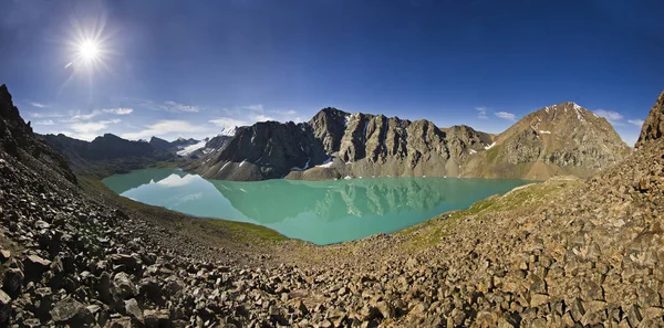Hermoso lago de montaña azul con piedras en la orilla y nubes en el cielo azul — Foto de Stock