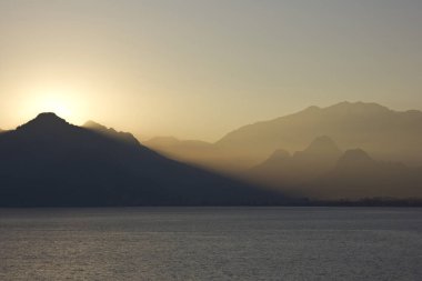 Deniz arka plan üzerinde Dağları ile yukarıda sarı günbatımı
