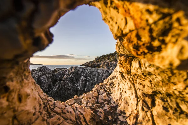 Uitzicht vanaf hole in steen op vulkanische strand omgeven door bergen bij zonsopgang — Stockfoto