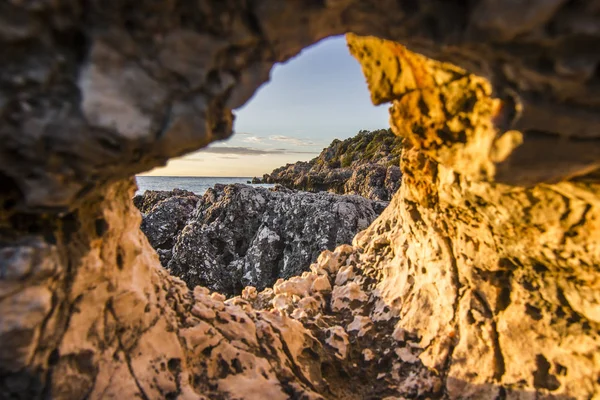 Uitzicht vanaf hole in steen op vulkanische strand omgeven door bergen bij zonsopgang — Stockfoto